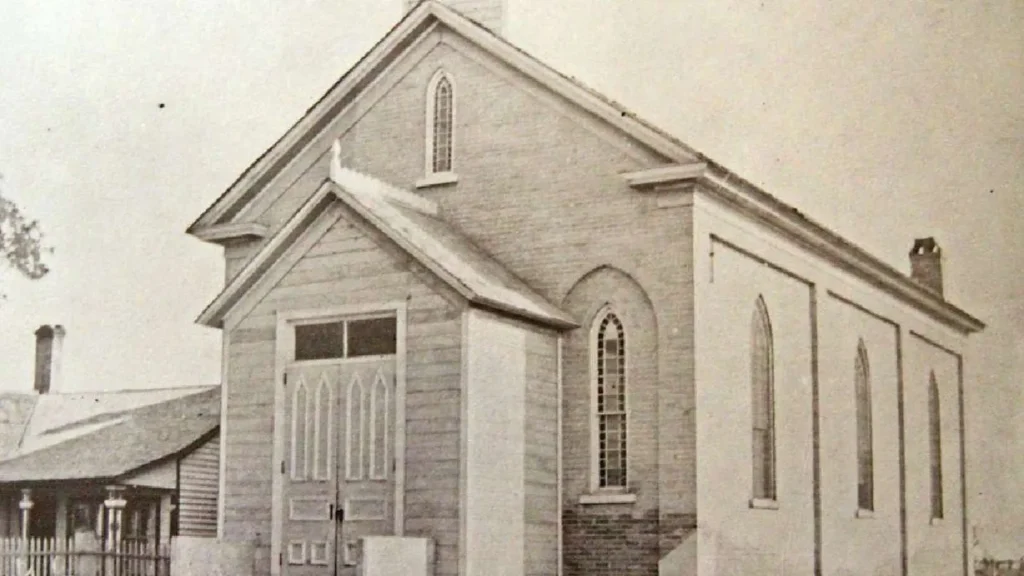 A historical photo of a church in black and white. The aging of it has turned the photo slightly sepia-toned. 