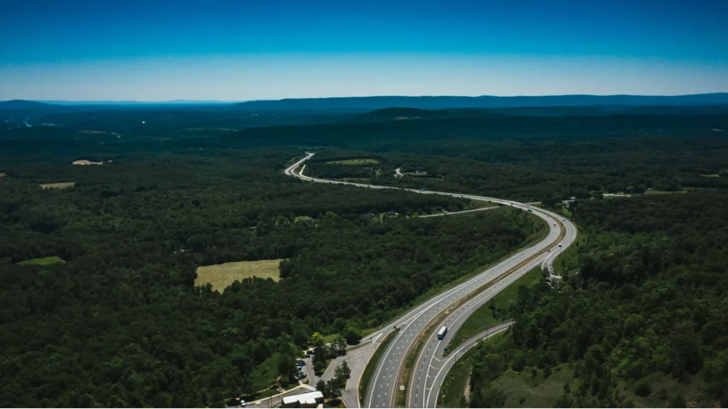 An aerial photo of a roadway as it stretches across the land into the horizon where the land and sky meet.