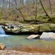 Some smaller falls in the J.C. WMA in Louisiana. The water is surrounded by dense foliage and trees.