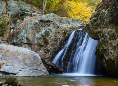 A photo of the Kilgore Falls as the light peeks through the fall colored trees.