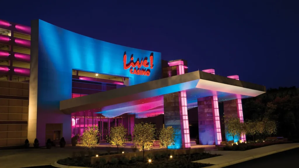 A photo of the outside of the Maryland Live! Casino at night. It's lit up with pink and blue lights. 