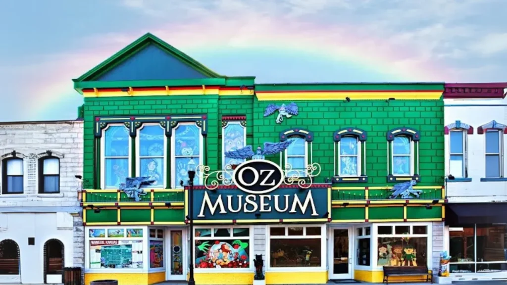 A photo of the exterior of the OZ Museum, bright green and yellow, with a rainbow behind it. 