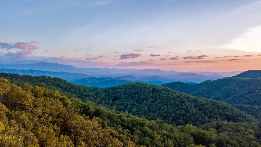 Blue Ridge Mountains during the summer at dusk. The sky is tones of pinks, purples, oranges, and blues as the sun sets behind the mountains.