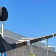The Duncan Stick in B.C., Canada sits attached to a building with a bright blue sky behind it.