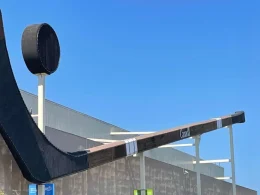 The Duncan Stick in B.C., Canada sits attached to a building with a bright blue sky behind it.