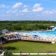 An aerial of a portion of the Buccaneer State Park. In it is a portion of the water park, bright blue sky, and green grass.