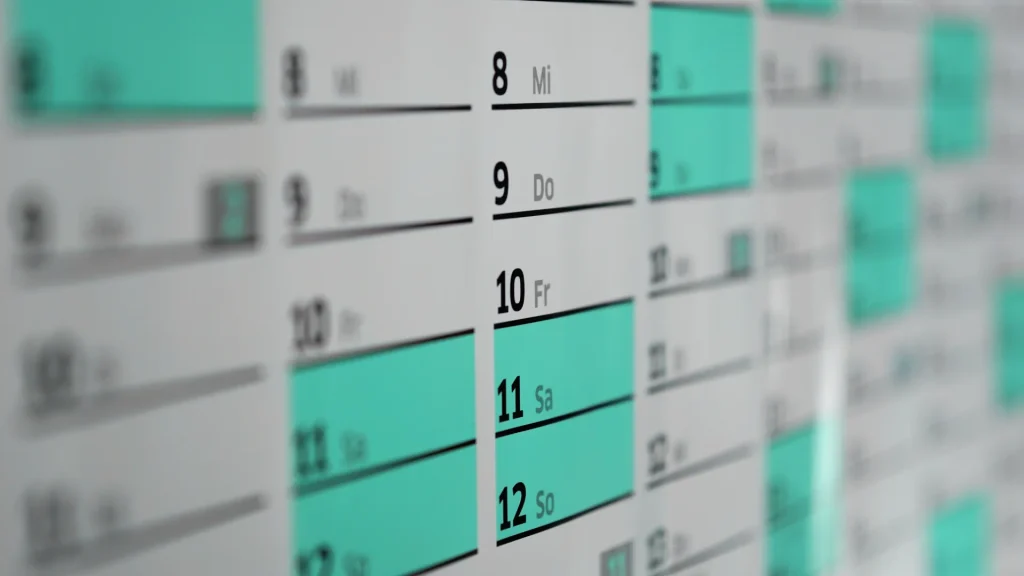 A close up photo of a calendar with dates highlighted in turquoise blue.
