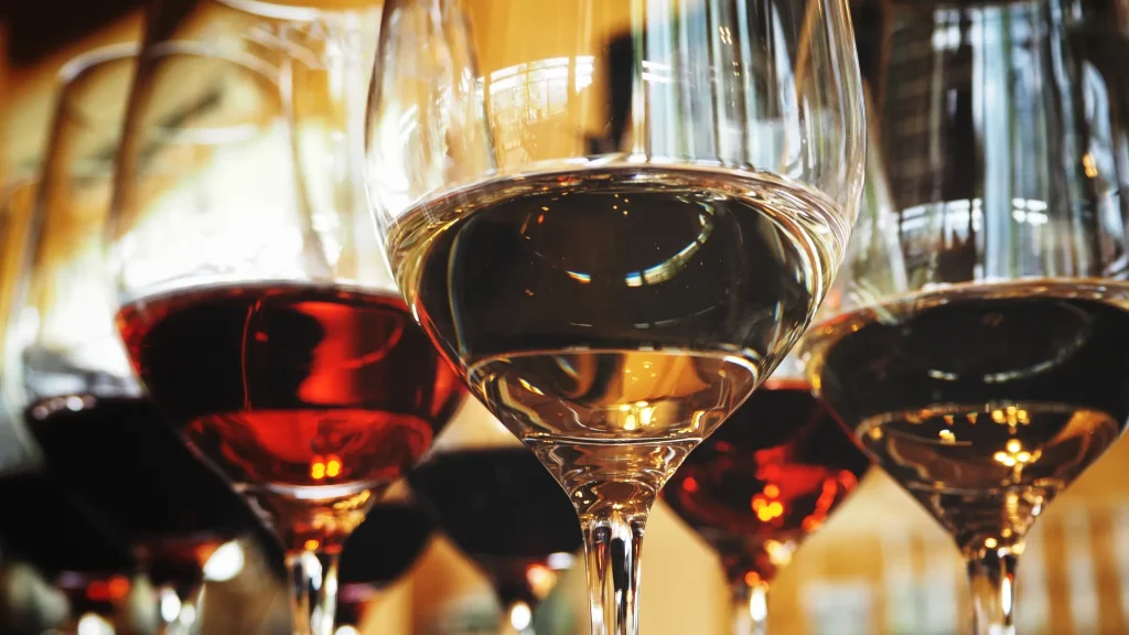 Seven glasses of wine with varying wines in them in a close shot of the wines. 