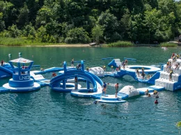 France Park aerial of an inflatable play park floating atop the lake within the park as people play on it.