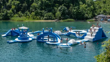 France Park aerial of an inflatable play park floating atop the lake within the park as people play on it.