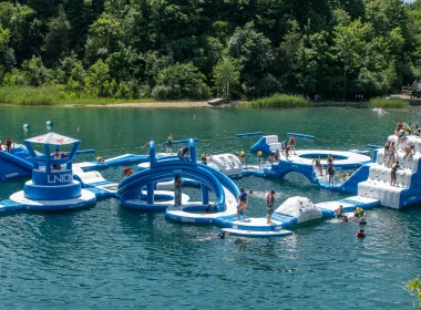 France Park aerial of an inflatable play park floating atop the lake within the park as people play on it.