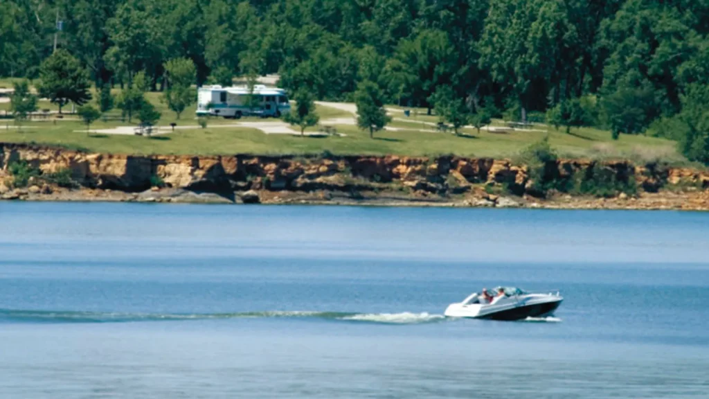 The lake at Kanopolis State Park with a bayliner-style boat speeding atop the water, creating a wake behind it.