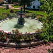 An elaborate fountain the the town of Long Grove. It is surrounded by red brick and green foliage and manicured lawn.