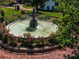 An elaborate fountain the the town of Long Grove. It is surrounded by red brick and green foliage and manicured lawn.