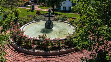 An elaborate fountain the the town of Long Grove. It is surrounded by red brick and green foliage and manicured lawn.