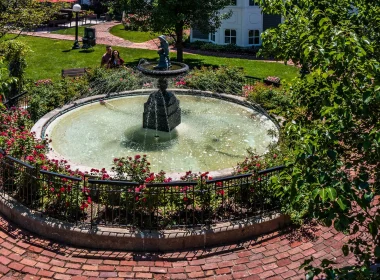 An elaborate fountain the the town of Long Grove. It is surrounded by red brick and green foliage and manicured lawn.